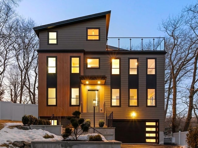 contemporary house with an attached garage, driveway, and fence