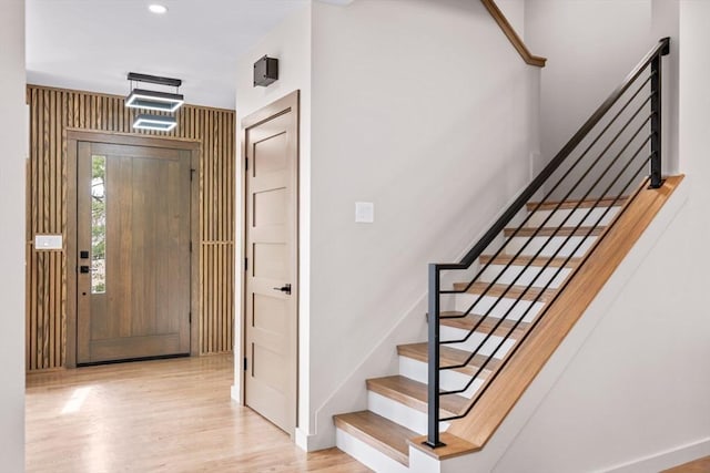 foyer with stairway, baseboards, and wood finished floors