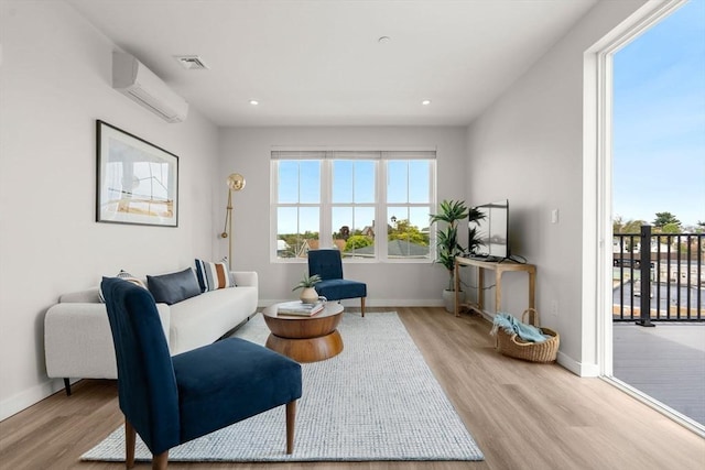 living area with baseboards, light wood-style floors, visible vents, and a wall mounted AC