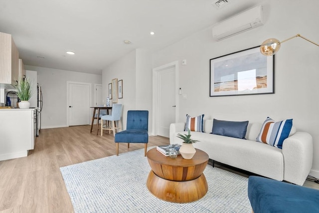 living area featuring a wall unit AC, visible vents, baseboards, light wood-style floors, and recessed lighting