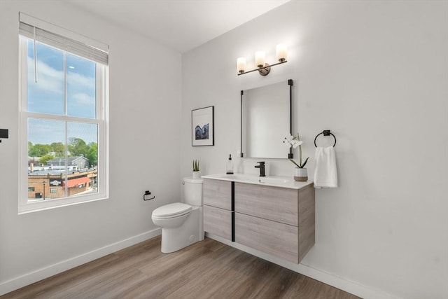 bathroom featuring baseboards, vanity, toilet, and wood finished floors