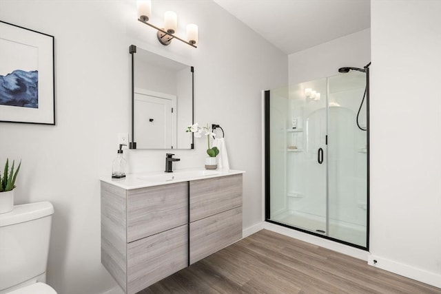 bathroom featuring vanity, toilet, wood finished floors, and a shower stall