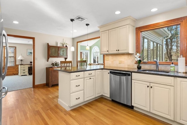 kitchen with visible vents, light wood-style flooring, a sink, stainless steel dishwasher, and a peninsula