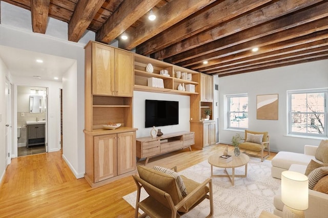 living room with a healthy amount of sunlight, beamed ceiling, light wood-type flooring, and sink