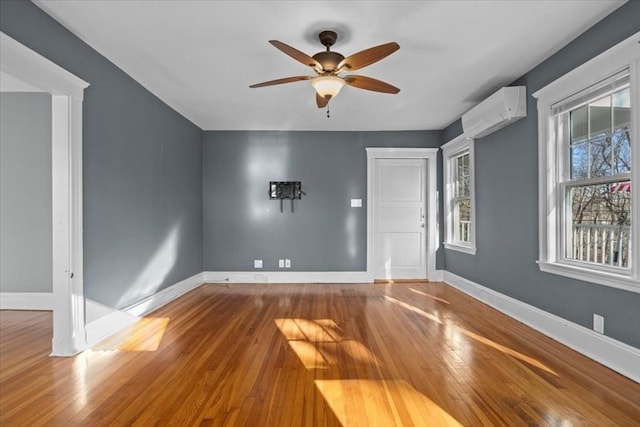 spare room with hardwood / wood-style floors, ceiling fan, and a wall mounted air conditioner