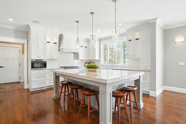 kitchen featuring crown molding, a kitchen breakfast bar, stainless steel oven, and a sink