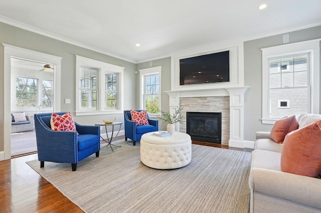 living area with crown molding, baseboards, a healthy amount of sunlight, and wood finished floors
