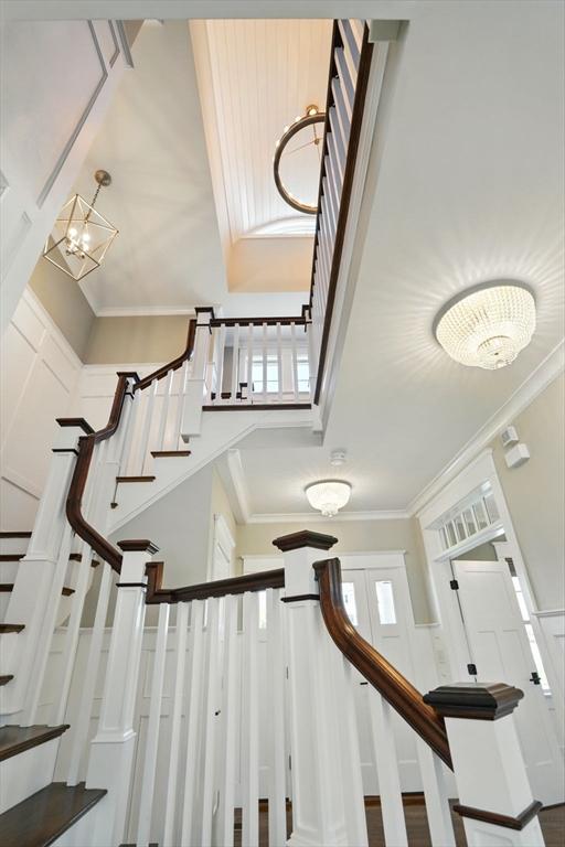 stairway featuring a towering ceiling, ornamental molding, and a notable chandelier