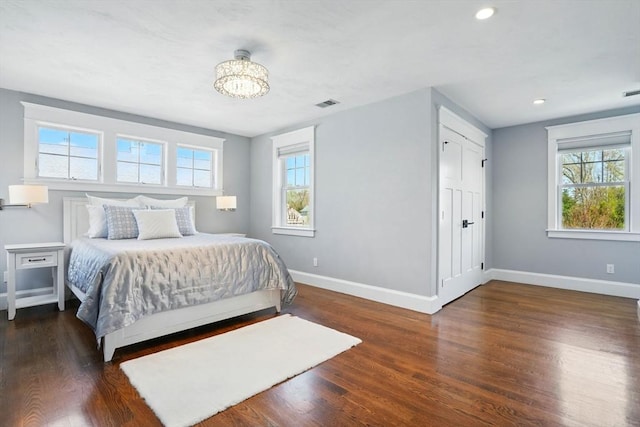 bedroom featuring baseboards, a chandelier, wood finished floors, and visible vents
