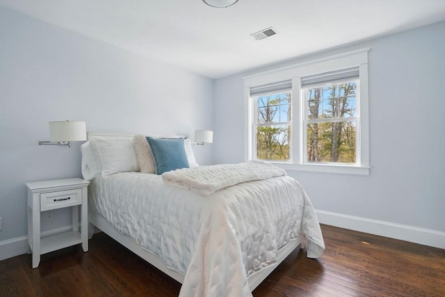 bedroom featuring baseboards, wood finished floors, and visible vents
