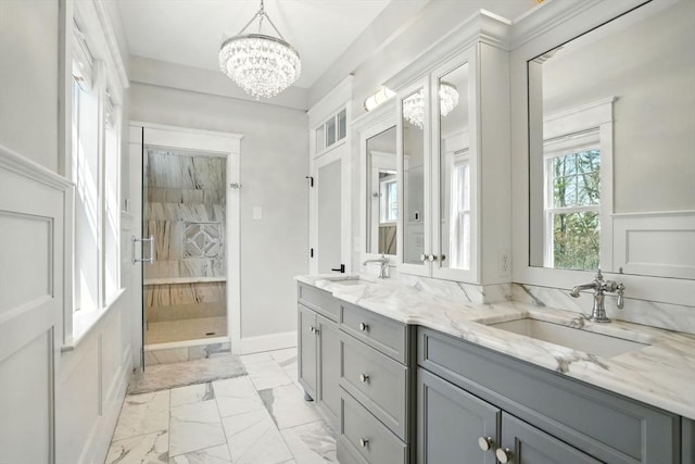 bathroom with an inviting chandelier, a sink, marble finish floor, and a stall shower