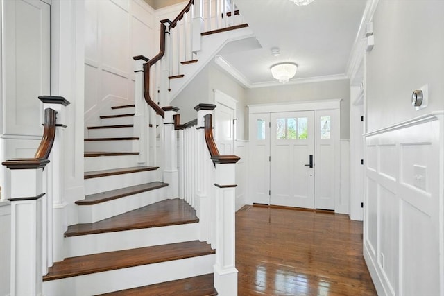 foyer entrance with crown molding, a decorative wall, stairway, and hardwood / wood-style floors