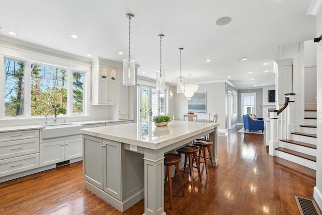 kitchen featuring a center island, a sink, dark wood-type flooring, and crown molding