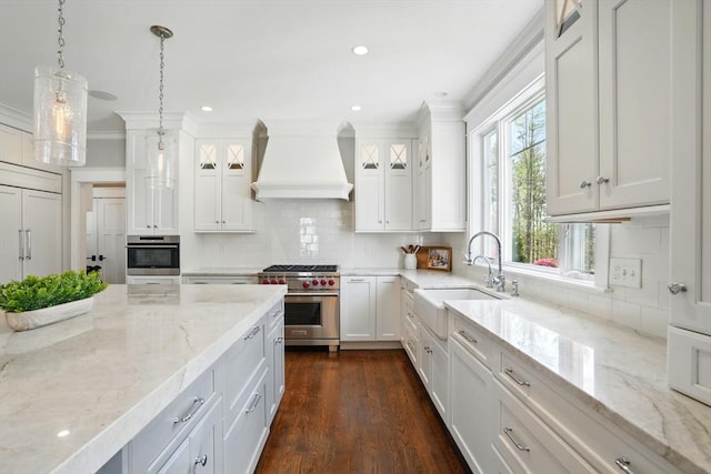 kitchen with crown molding, a sink, stainless steel appliances, white cabinetry, and custom range hood