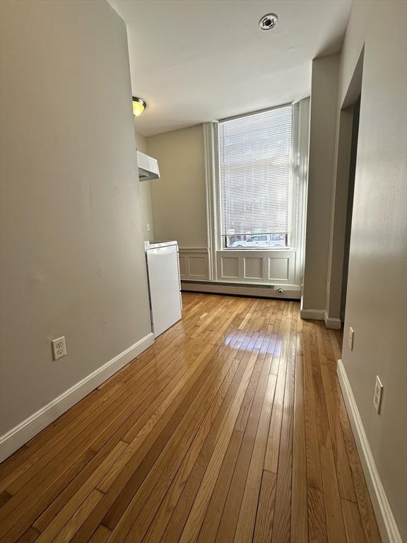 empty room with baseboard heating and light hardwood / wood-style floors