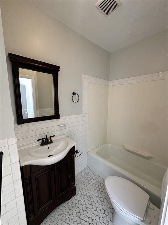 full bathroom with vanity, shower / tub combination, tile walls, tile patterned flooring, and toilet