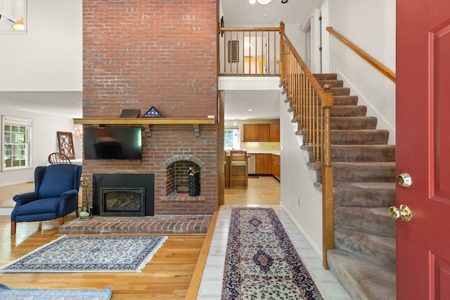 12 Robin Ln, Pepperell, MA 01463 - living room with a brick fireplace, light wood finished floors, stairs, a towering ceiling, and baseboards