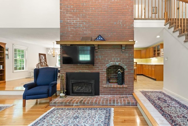 12 Robin Ln, Pepperell, MA 01463 - living area featuring a brick fireplace, light wood finished floors, baseboards, and a chandelier