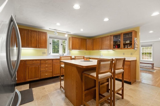 12 Robin Ln, Pepperell, MA 01463 - kitchen featuring freestanding refrigerator, brown cabinetry, light countertops, a kitchen bar, and a kitchen island