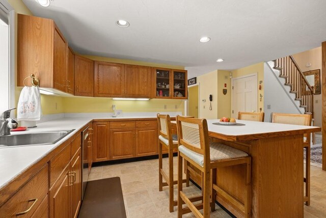 12 Robin Ln, Pepperell, MA 01463 - kitchen with a breakfast bar, a sink, recessed lighting, glass insert cabinets, and brown cabinets