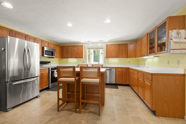 12 Robin Ln, Pepperell, MA 01463 - kitchen featuring stainless steel appliances, light countertops, glass insert cabinets, recessed lighting, and a breakfast bar area