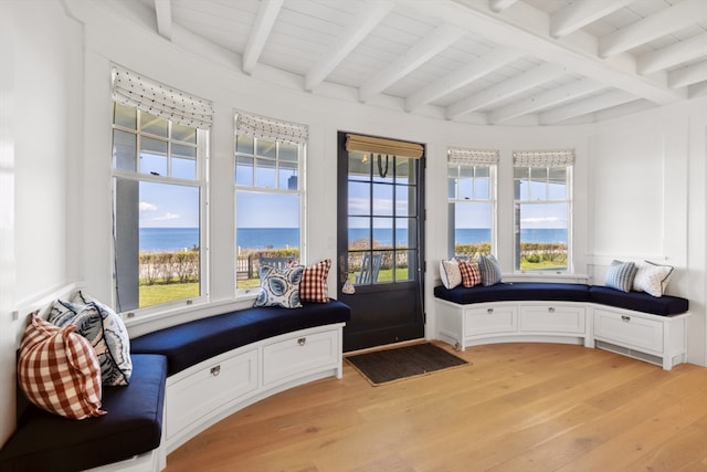 sitting room featuring beamed ceiling, plenty of natural light, and a water view