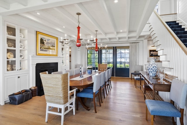 dining room featuring beamed ceiling, light wood-type flooring, and a chandelier