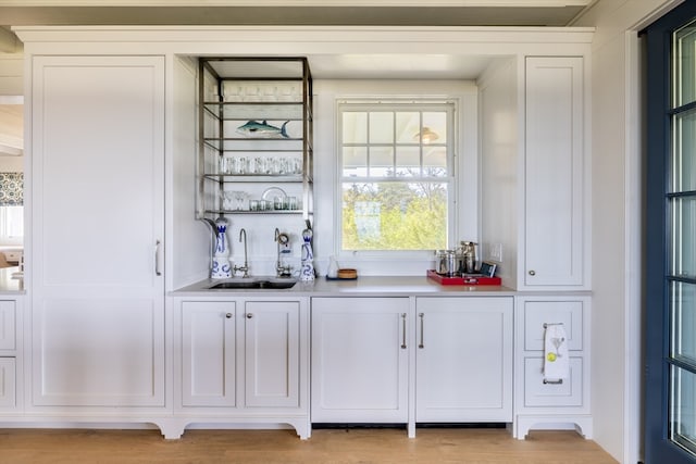 bar featuring white cabinets, sink, and light wood-type flooring