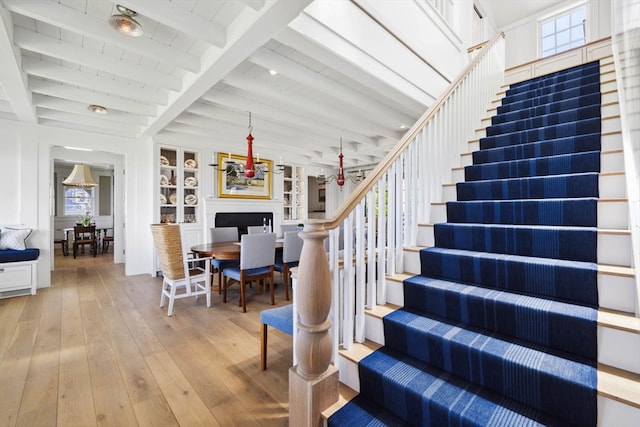 staircase with ceiling fan, beam ceiling, and light wood-type flooring