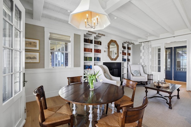 dining space featuring a chandelier, hardwood / wood-style floors, beam ceiling, built in shelves, and french doors