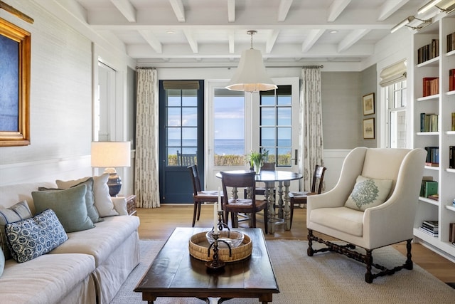 living room featuring beam ceiling, a water view, and light hardwood / wood-style floors