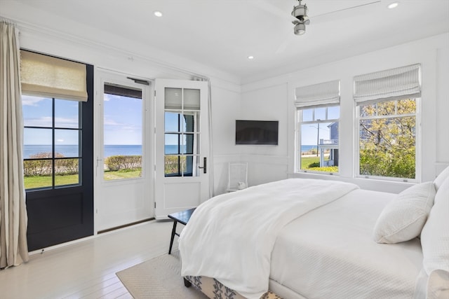 bedroom featuring ceiling fan, a water view, and hardwood / wood-style floors