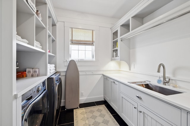 washroom with sink, washing machine and clothes dryer, and dark tile floors