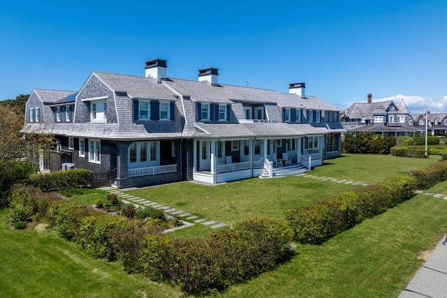 rear view of property with covered porch and a lawn