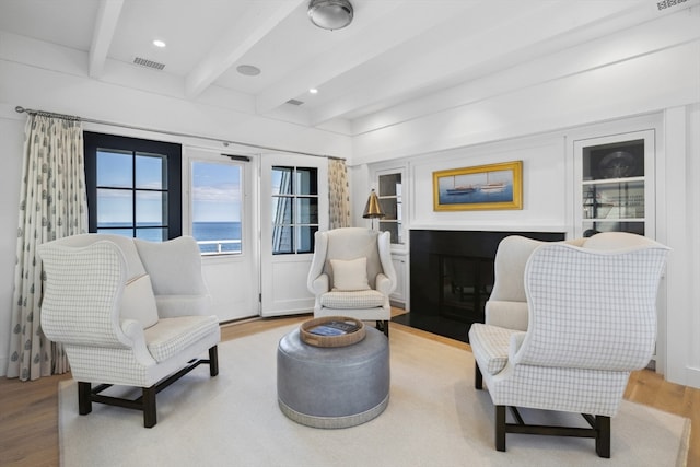 sitting room with beamed ceiling, light hardwood / wood-style floors, and a water view