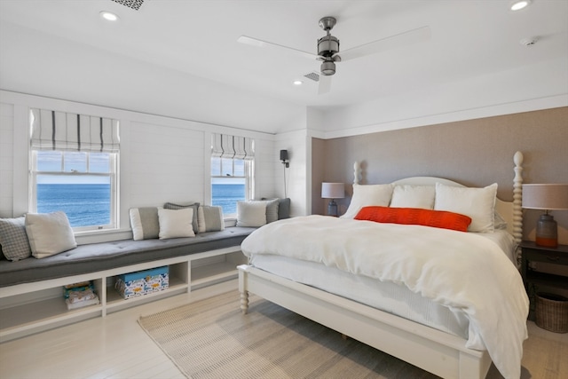 bedroom with wood-type flooring, a water view, and ceiling fan