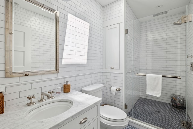 bathroom with vanity with extensive cabinet space, an enclosed shower, toilet, and tile walls