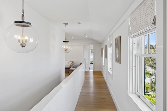 hallway featuring vaulted ceiling, hardwood / wood-style flooring, and an inviting chandelier