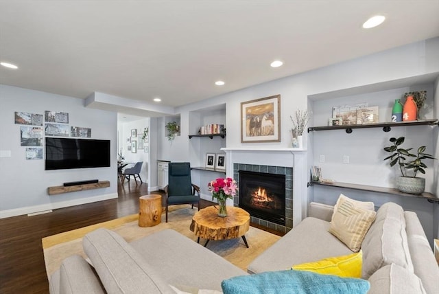 living area featuring baseboards, a tiled fireplace, wood finished floors, and recessed lighting