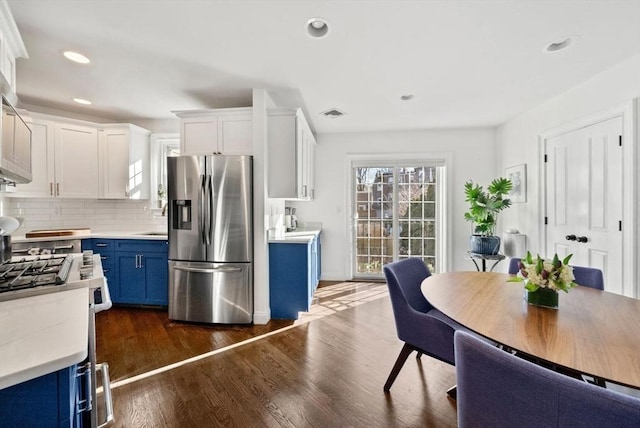 kitchen with light countertops, blue cabinetry, dark wood-type flooring, and stainless steel refrigerator with ice dispenser