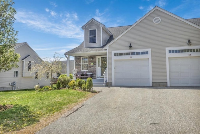 view of front of property featuring asphalt driveway, a garage, covered porch, and a shingled roof