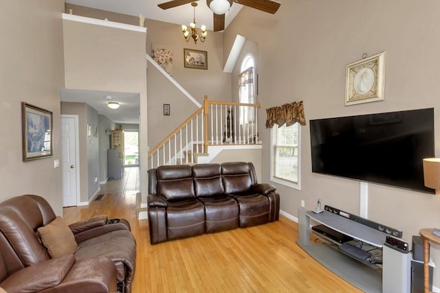 living area featuring a high ceiling, wood finished floors, plenty of natural light, stairs, and baseboards