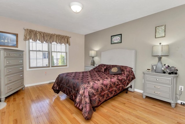 bedroom featuring light wood finished floors and baseboards