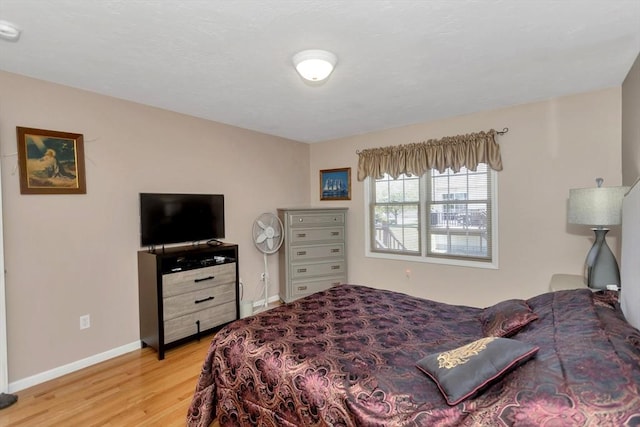bedroom featuring light wood finished floors and baseboards