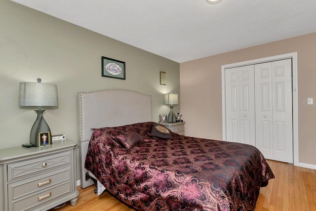 bedroom with light wood-style flooring, a closet, and baseboards