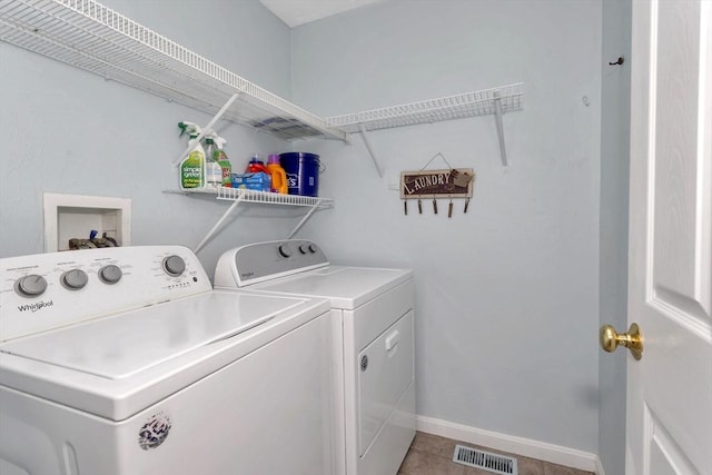 laundry area featuring washer and clothes dryer, light tile patterned flooring, and baseboards