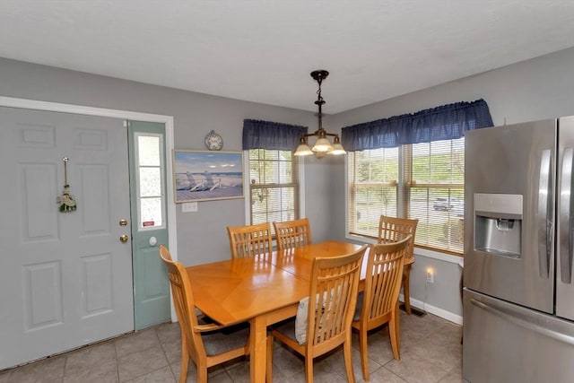 dining space featuring light tile patterned flooring, baseboards, and a chandelier