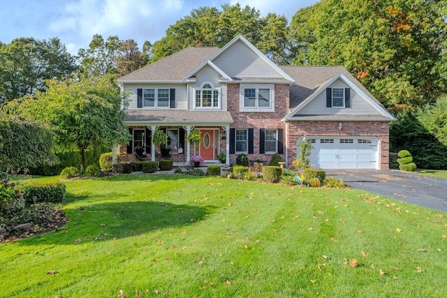 view of front of home with a garage, brick siding, aphalt driveway, and a front yard