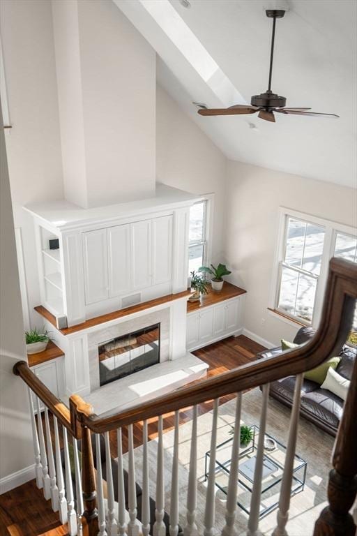 interior space featuring a skylight, baseboards, a ceiling fan, wood finished floors, and high vaulted ceiling