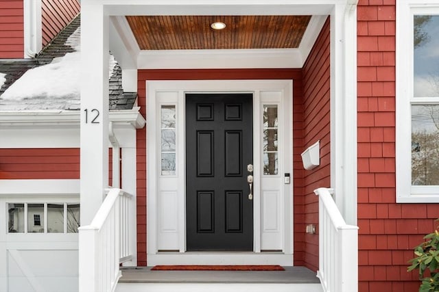 view of exterior entry featuring a shingled roof